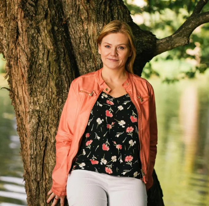 Michaela Jandorová v oranžové bundě u kmenu stromu